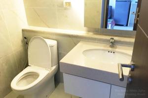 een badkamer met een toilet, een wastafel en een spiegel bij Astra White Suite 12 in Chiang Mai