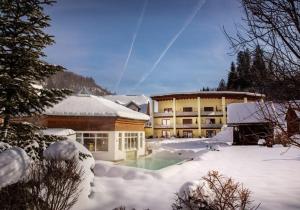 ein Gebäude mit einem Pool im Schnee in der Unterkunft Relax- & Wanderhotel Poppengut in Hinterstoder