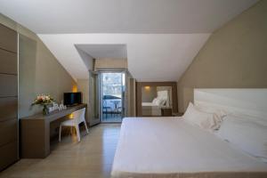 una camera con un grande letto bianco e una scrivania di Hotel San Rocco a Orta San Giulio