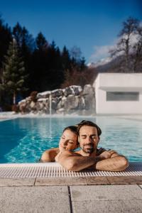 a man and woman are laying in a swimming pool at Relax- & Wanderhotel Poppengut in Hinterstoder