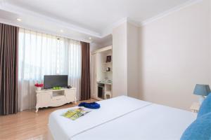 Habitación blanca con cama y TV en Phoenix Hotel Ha Long, en Ha Long