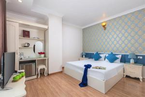 een slaapkamer met een groot wit bed en een televisie bij Phoenix Hotel Ha Long in Ha Long