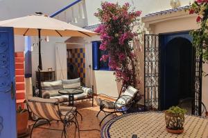 een patio met een tafel en stoelen en een parasol bij belle maison vue sur mer in Oualidia