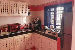 eine Küche mit weißen Schränken und einem schwarzen Kühlschrank in der Unterkunft belle maison vue sur mer in Oualidia