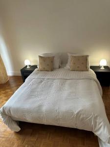 a white bed with two tables and two lamps at résidence Garches -St Cloud in Rueil-Malmaison