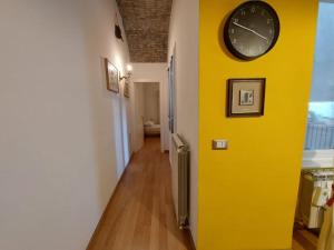 Una pared amarilla en un pasillo con un reloj. en La Terrazza, en Trieste