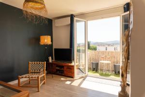 - un salon avec une télévision et une porte coulissante en verre dans l'établissement Le Blue Sea - Appt T3 classé 3 étoiles à 650m de la plage, au Lavandou