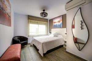 Un dormitorio con una cama, una silla y un espejo. en Dreams Port Cambrils Apartment, en Cambrils