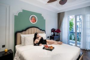 a woman laying on a bed with a tray of food at The An Nam Villa HaLong in Ha Long