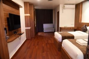 ein Hotelzimmer mit 2 Betten und einem Flachbild-TV in der Unterkunft Hotel Obsidian Blue in Itānagar