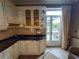 una cocina con armarios blancos y una puerta a un patio en Gîte L'Hôte-Antique en Bouillon