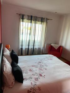 ein Schlafzimmer mit einem großen Bett und einem roten Stuhl in der Unterkunft Maison proche de la mer in Murtosa