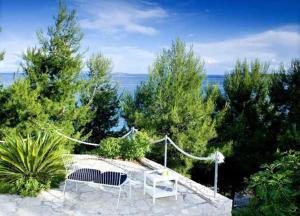a patio with two chairs and trees and the ocean at Villa Peljesac Majestic A Beautiful 8 Bedroom Villa Short Stroll Down the Path to the Beach in Orebić