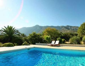 a swimming pool with a bench and mountains in the background at Villa Peljesac Majestic A Beautiful 8 Bedroom Villa Short Stroll Down the Path to the Beach in Orebić