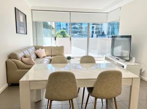 een woonkamer met een tafel en stoelen en een bank bij Charming One-Bed Apt in the Heart of Parramatta in Sydney