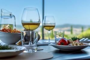 a table with two glasses of wine and a plate of food at AffittiBreviSiena - Palazzo Monaci Appartamento con piscina nelle crete Senesi in Asciano