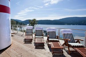 four chairs sitting on a deck overlooking a lake at Hotel Schiff am Schluchsee in Schluchsee