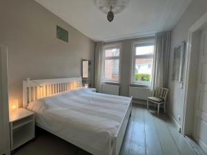 een slaapkamer met een wit bed en 2 ramen bij Am Hafen 13 in Glückstadt