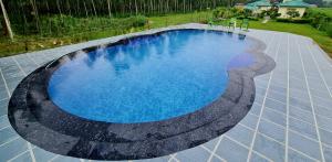 uma grande piscina com água azul num quintal em The Tiger Claw Resort em Ramnagar