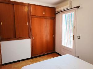 a bedroom with a bed and wooden cabinets and a window at Costa brava apartment, Estartit in Torroella de Montgrí