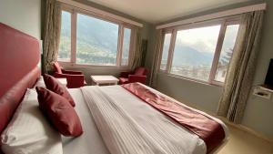 a bedroom with a bed and windows with a view at The View Meadow in Manāli