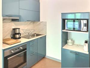 a blue kitchen with a sink and a microwave at Le Vallon des Sources in Digne-les-Bains