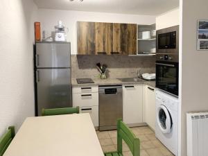 uma cozinha com um frigorífico e uma mesa com cadeiras verdes em Le Vallon des Sources em Digne-les-Bains