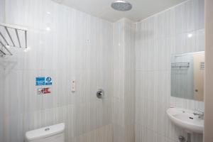 a white bathroom with a sink and a toilet at AVA Guesthouse Mitra RedDoorz Lampung in Bandar Lampung