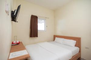 a bedroom with a white bed and a window at AVA Guesthouse Mitra RedDoorz Lampung in Bandar Lampung