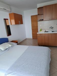 a bedroom with a white bed and a kitchen at Apartments Sabol Geist in Borovići