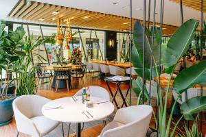 un restaurant avec des tables blanches, des chaises et des plantes dans l'établissement Parque Santiago V Official, à Playa de las Americas