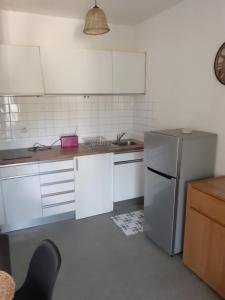 a kitchen with white cabinets and a stainless steel refrigerator at Entre terre et mer in Oloron-Sainte-Marie