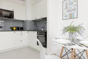 a white kitchen with a white table and white chairs at Pet-Friendly Apartment Prymasa Tysiąclecia by Renters in Warsaw