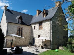 a large brick building with tables and umbrellas at Manoir de la coudre in Changé