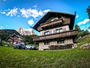 a building in the mountains with cars parked next to it at Chalet della Civetta 