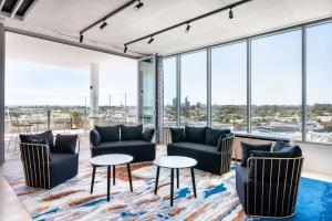 a living room with couches and tables and large windows at Vibe Hotel Subiaco Perth in Perth