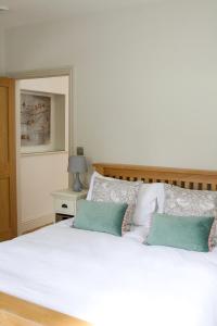 a bedroom with a white bed with two green pillows at Cromhall Farm in Chippenham