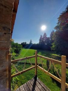 a wooden fence in a field with the sun in the sky at Maison de la nature in Bussière-Galant