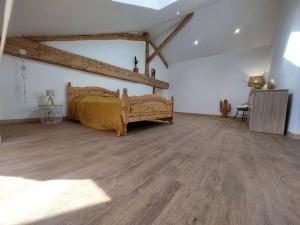 a bedroom with a bed and a wooden floor at Maison de la nature in Bussière-Galant