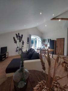a living room with a couch and a vase with flowers at Maison de la nature in Bussière-Galant