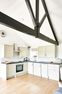 uma cozinha com armários brancos e piso em madeira em Cromhall Farm em Chippenham