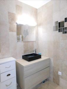 La salle de bains est pourvue d'un lavabo noir et d'un miroir. dans l'établissement Stunning T4 Musardière, à Antibes