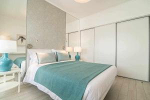 um quarto branco com uma cama grande e um cobertor azul em RECANTO DO AÇOR Holiday Accommodation em Ponta Delgada