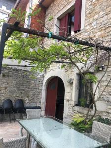 a glass table in front of a building with a red door at meublé neuf avec jardin in Clairvaux-les-Lacs