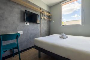 a bedroom with a bed and a chair and a tv at ibis budget Nanterre la Defense in Nanterre