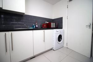 a white kitchen with a washing machine in it at Lovely Studio Flat, Free Parking-Near City Centre in Swansea