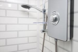 a shower head in a bathroom with white tiles at Lovely Studio Flat, Free Parking-Near City Centre in Swansea