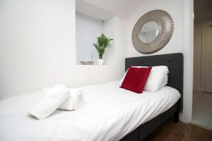 a bedroom with a white bed with red pillows and a mirror at Lovely Studio Flat, Free Parking-Near City Centre in Swansea