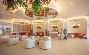 a lobby with white chairs and tables and people in it at RH Silene Hotel & Spa 4 Sup in Castellón de la Plana