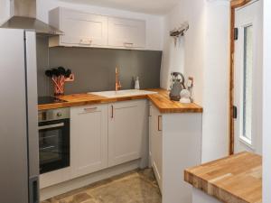 eine Küche mit weißen Schränken und einem Waschbecken in der Unterkunft Lydgate Cottage in Eyam